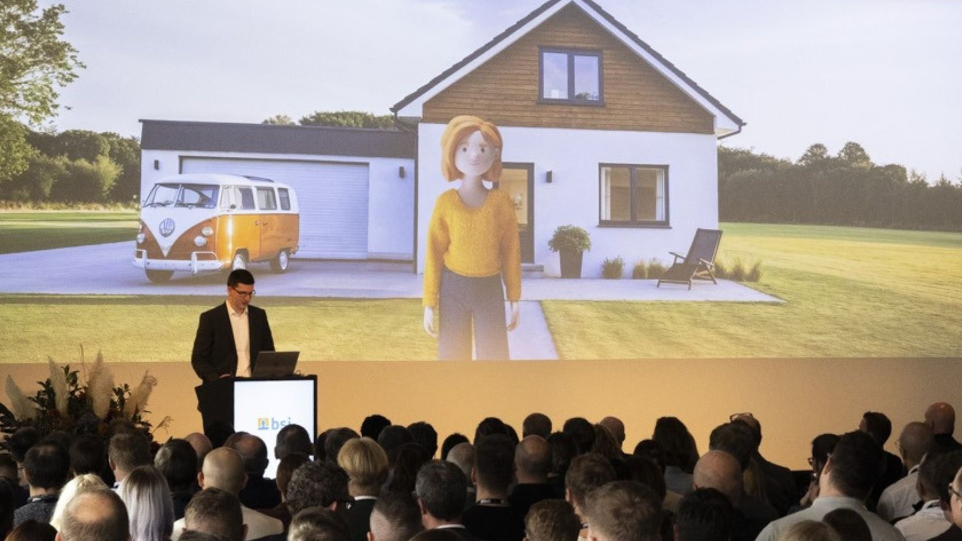 Olav Lenz präsentiert beim Customer Summit 2025 auf einer Bühne vor Publikum die 3D-Kundin Lena Meier vor Einfamilienhaus mit Garage. Die Szene zeigt eine innovative Produktdemonstration und veranschaulicht Customer Relationship Management, digitale Beratung und personalisierte Customer Experience mit der BSI Customer Suite.