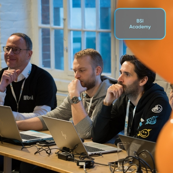 Participants of the BSI Academy at the BSI Campus 2025 working intently on their laptops; a light grey "BSI Academy" button is visible at the top right.
