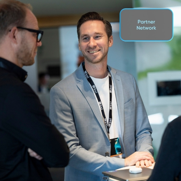 A BSI team member talking with a partner at the BSI Customer Summit 2025; a light grey "Partner Network" button is visible at the top right.