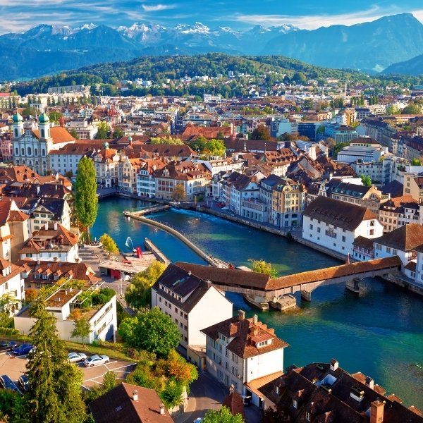 Luftaufnahme der Altstadt von Luzern mit der historischen Kapellbrücke über die Reuss, umgeben von farbigen Häusern, Kirchen und dem Vierwaldstättersee vor alpiner Kulisse. Seit 2024 ist Luzern zudem der jüngste Schweizer Standort von BSI Software und stärkt die regionale Präsenz des Unternehmens.
