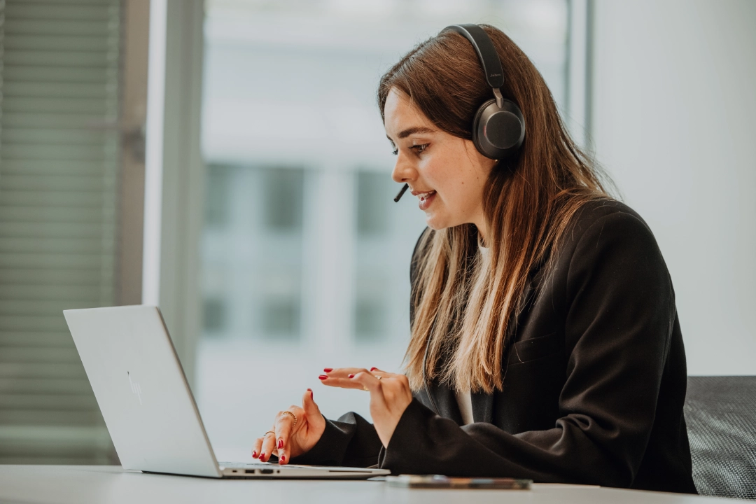 Mitarbeitende im Praktikum oder Werkstudium arbeitet mit Headset am Laptop und nimmt an einem virtuellen Austausch teil – flexible Arbeitsmodelle, persönliche Entwicklung und praxisnahe Einblicke bei BSI Software.