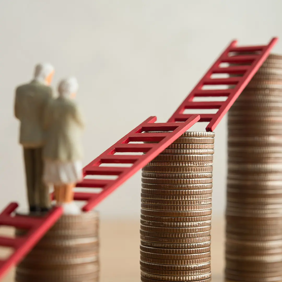 Zwei Miniaturfiguren eines älteren Paares stehen auf einem Münzstapel. Rote Leitern verbinden mehrere unterschiedlich hohe Münzstapel und symbolisieren den langfristigen Vermögensaufbau für die Altersvorsorge. Das Titelbild illustriert ein Interview mit BSI Software Vorstandsmitglied Burkhard Oppenberg über die Chancen des Altersvorsorgedepots für Versicherer.