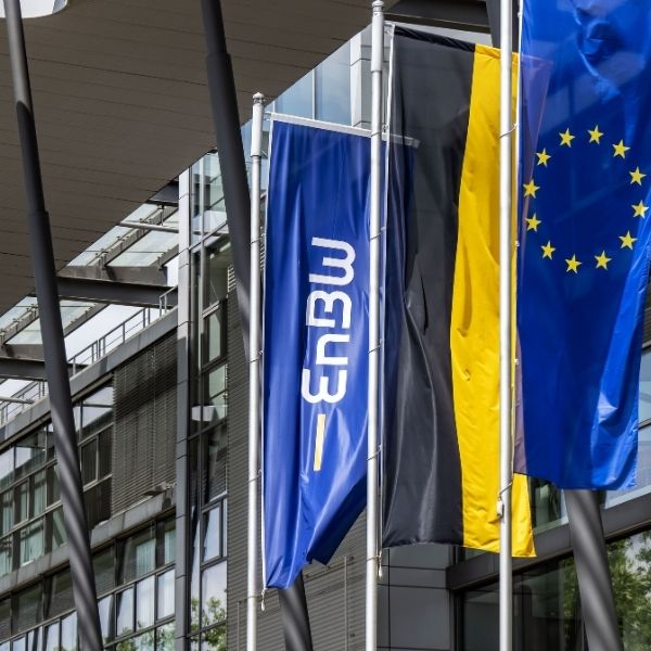 Exterior view of a modern office building with the flags of EnBW and the European Union waving – a visual statement of the new partnership between energy company EnBW and BSI in the field of Customer Relationship Management.